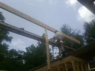 Carpenter setting a ridge beam over a new addition frame — Ice Dam Removal by Roofing Brothers in Harbor City