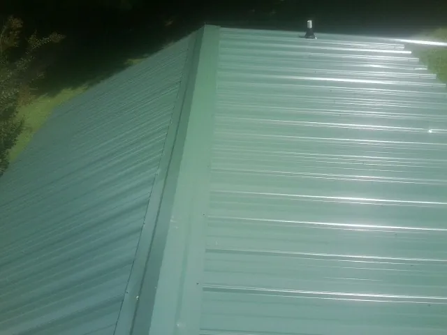 New green metal panels meeting at the ridge of a roof — Flat Roof Repair work by our crew in Harbor City