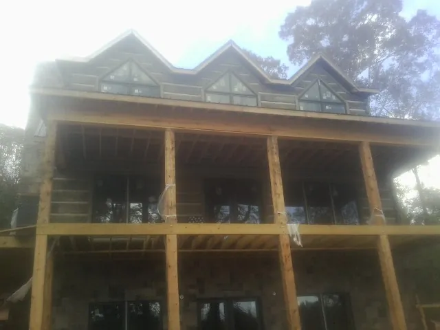 Dormers and porch framing on a large log home under construction — Roof Coating work by our crew in Harbor City