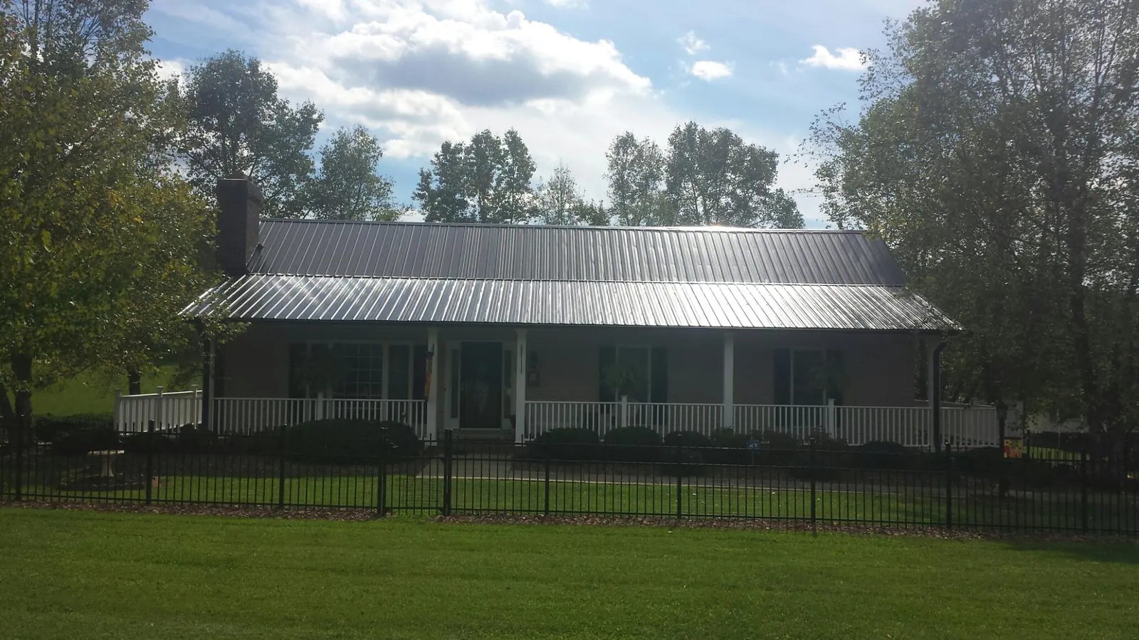 Gray metal roof on a brick ranch with a full width front porch — Gutter Guard Installation work by our crew in Harbor City