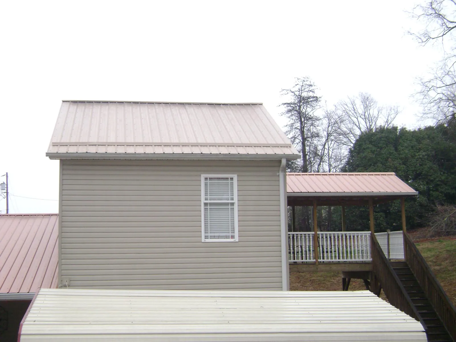 Tan metal roofs on a two story addition and attached porch, from a Roof Replacement job in Harbor City