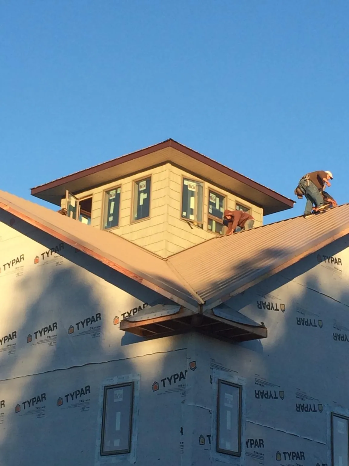 Roofers working around a rooftop cupola on a new metal roof at sunset — Roof Waterproofing in Harbor City by Roofing Brothers